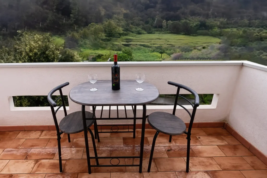 The Casa Bruna balcony with a small table and chairs, overlooking the green of Arbus